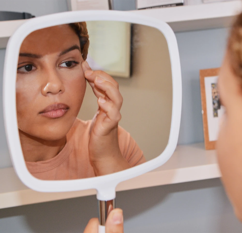 Female patient examines her face in the mirror